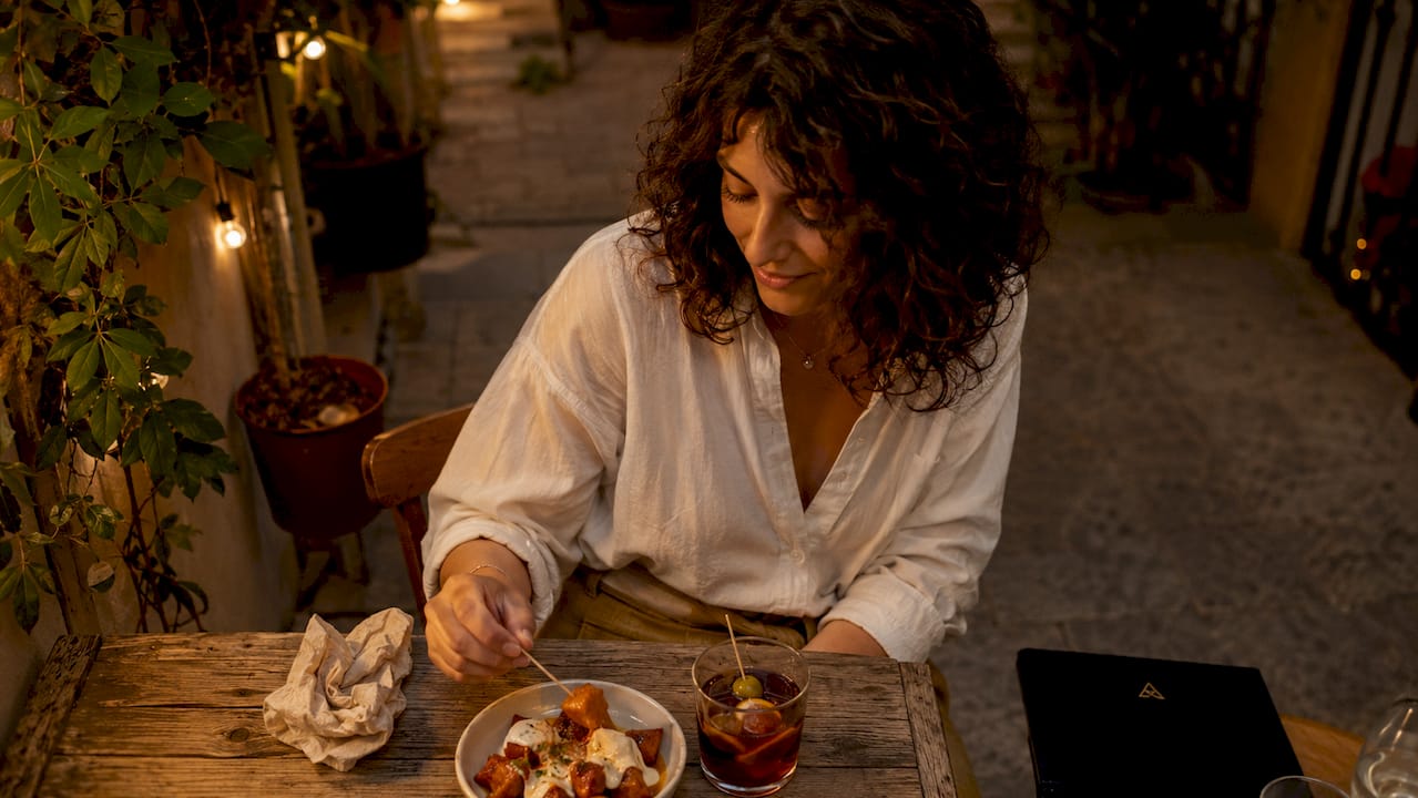 Una mujer saborea una tapa tradicional en una terraza del Born mientras cae la tarde.