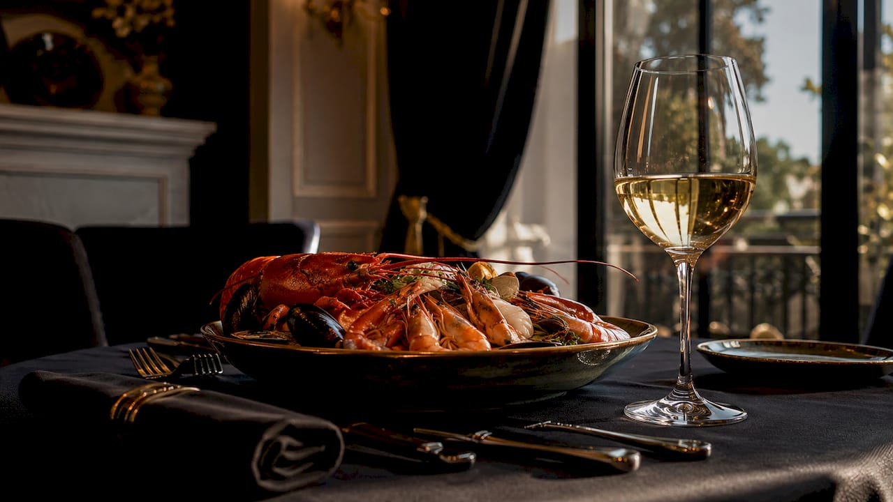 Una mesa sofisticada servida con mariscos frescos y una copa de vino blanco para acompañar.
