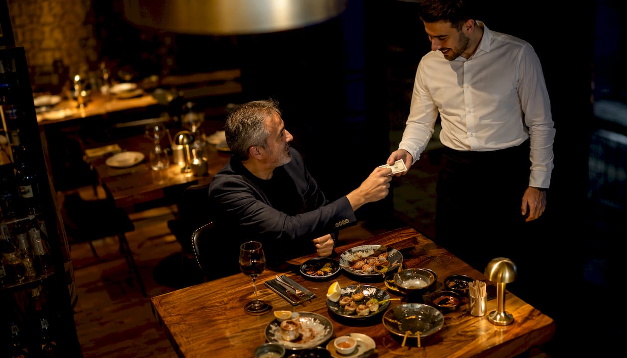 Un hombre deja propina al camarero en un restaurante de Barcelona.