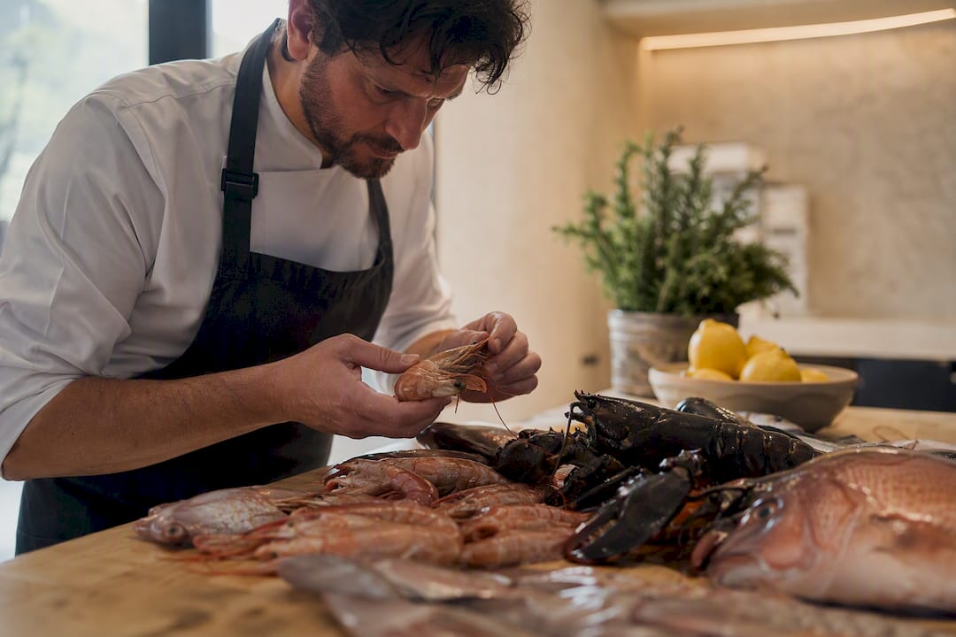 Chef manipulando mariscos frescos sobre la encimera